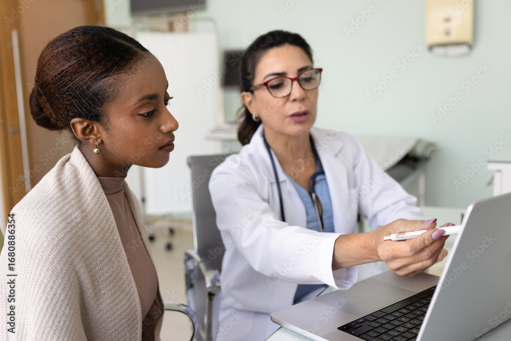 Fototapeta premium Mature female doctor show medical information to patient on laptop