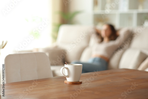 Cuadro en lienzo Coffee cup in foreground and woman relaxing in background
