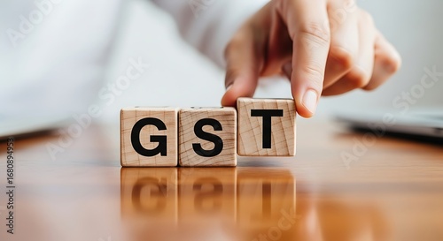 Hand arranging wooden blocks spelling gst symbolizing goods and services tax and financial planning