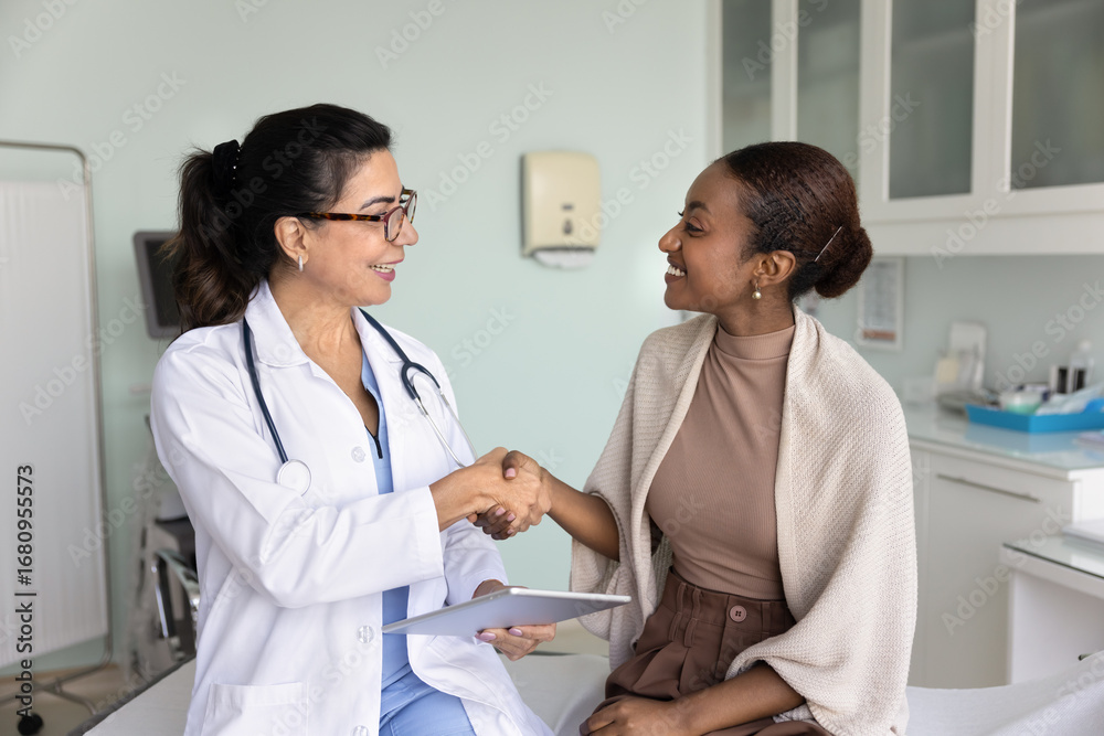 Fototapeta premium Mature 60s female doctor and woman patient share joyful handshake