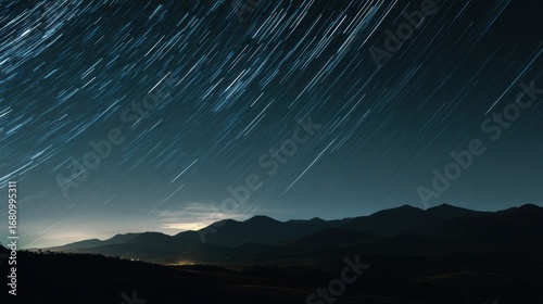 A time-lapse style streak of stars moving across a dark night sky above a mountain range, cinematic composition