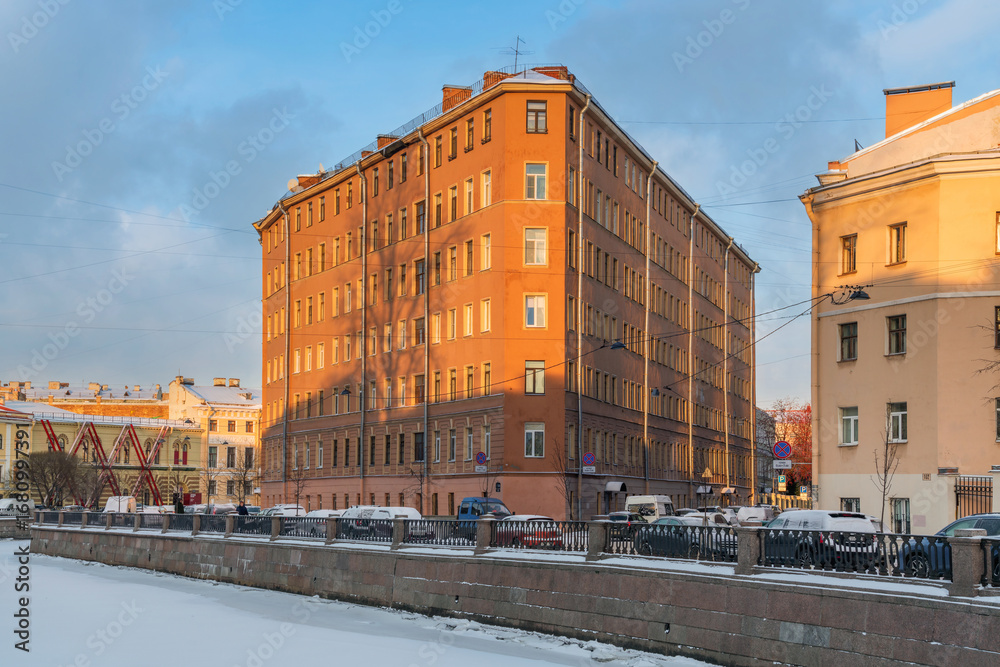 Obraz premium View of a residential building in the shape of an iron on the embankment of the Griboyedov Canal on a sunny winter day, St. Petersburg, Russia