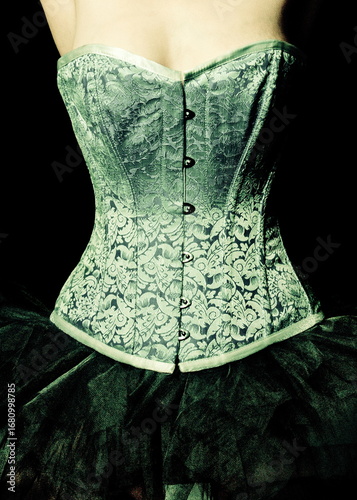 A woman wearing a green corset and a black skirt.