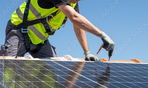 Photos Workers install solar panels on a sunny day at a residential rooftop in an urban