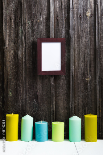 empty picture frame, candles on white table, old weathered wooden wall background