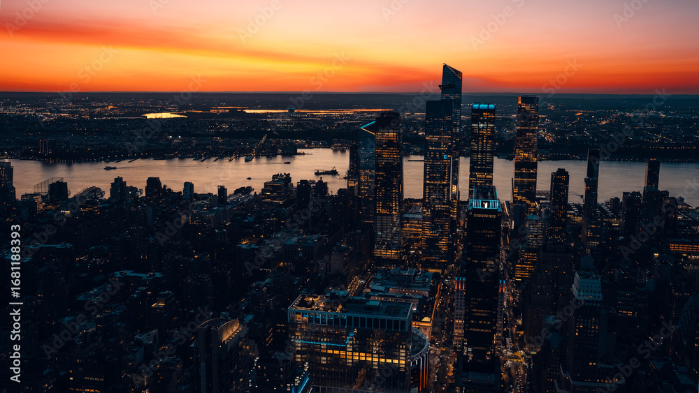 Fototapeta premium Lower Manhattan skyline at sunset seen from Brooklyn with glowing skyscrapers and river reflections, HDR