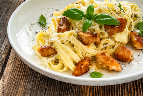 Foto Classic creamy chicken alfredo fettuccine pasta on wooden table
