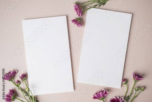 White blank greeting or invitation card with purple flower decoration on beige background.