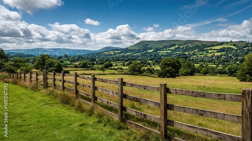 A wooden fence with green fields and blue skies in the background, showcasing its natural beauty under rolling hills, is perfect for expressing a rustic landscape or home décor.