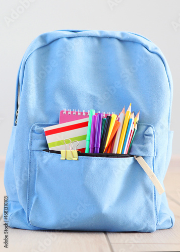 School backpack and stationery in a bright room.. Vertical photo format