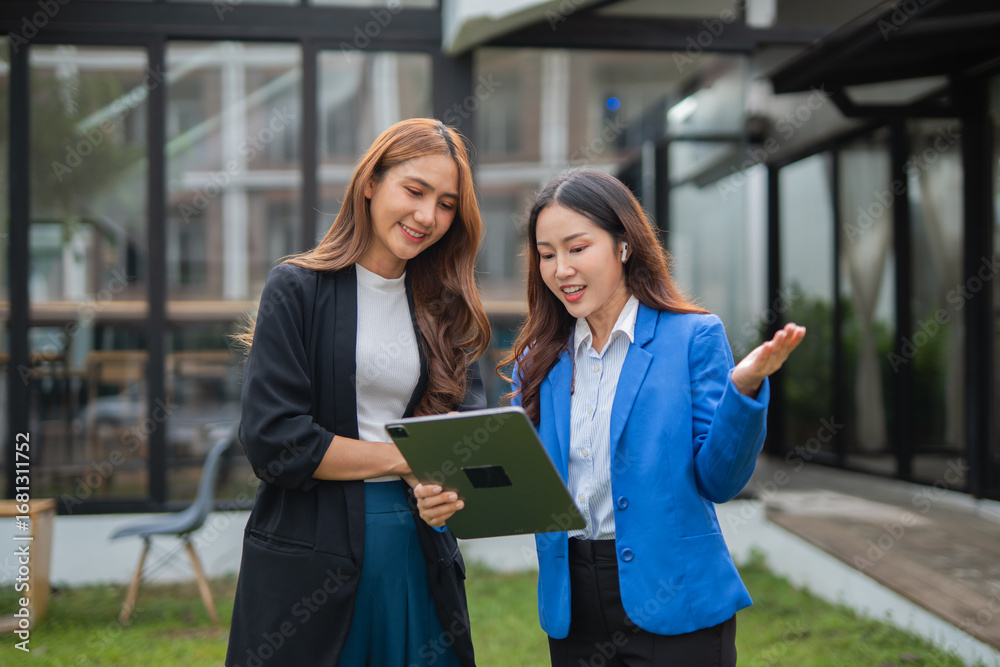 Fototapeta premium Asian businesswoman using digital laptop while standing in front of modern building. Attractive female employee working in front of office.