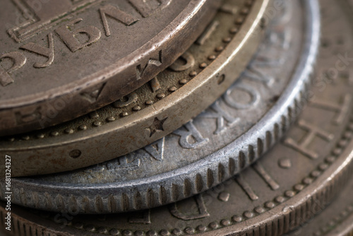 Stacked various coins close up, uncirculated coins with corrosion, dents and scratch damage, edges are reeded, decorated and with inscription