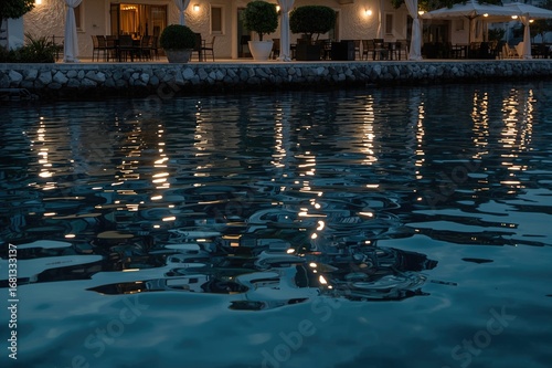 Evening tranquility captured in the mirrored surface of serene coastal waters with a terrace view.
