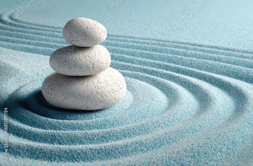 Three white stones balanced on a light blue sand zen garden