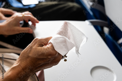 Air travel passenger preparing anti-bacterial wet wipes to sanitize personal space in air plane for hygiene reasons
