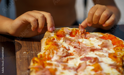 View of children's hands tearing a piece from a pinsa with cheese and ham. Fast food on the beach. Street food. traditional Italian food. Pinsa