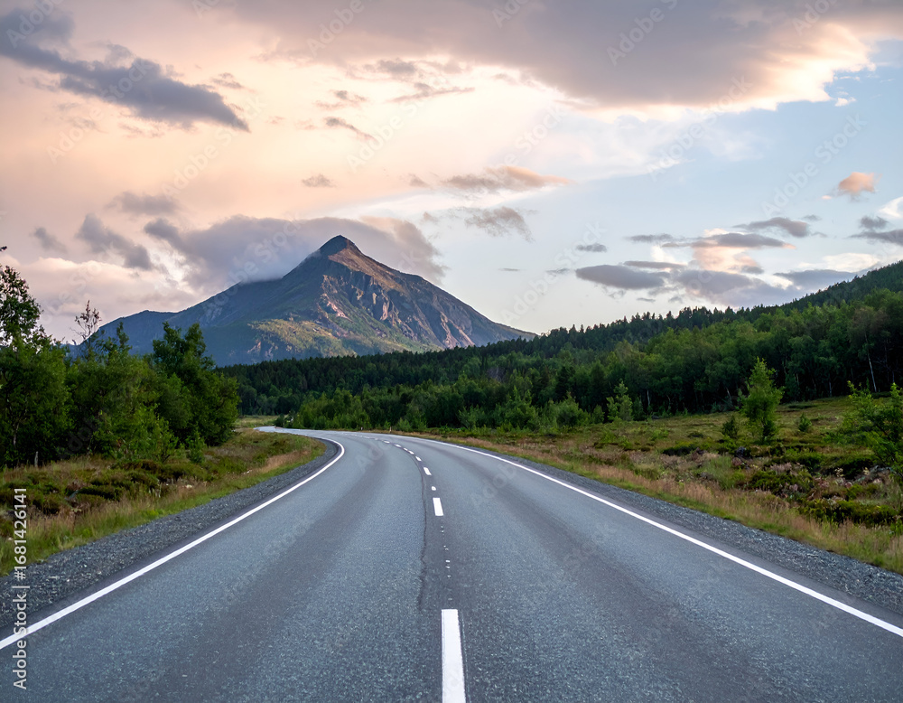 Fototapeta premium Scenic mountain road winding through a vibrant forest at sunset, inviting travel and adventure into a serene landscape. Perfect for journeys.