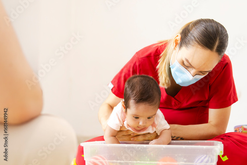 Obraz na plátně Latina physiotherapist performs early stimulation with water and balls for a 5-month-old baby in a clinic, reflecting inclusion, health, and child development