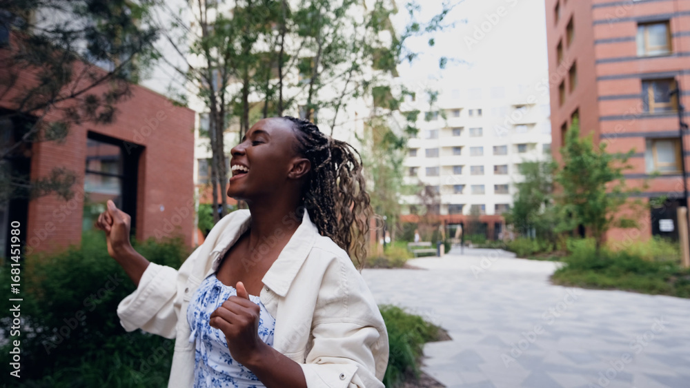 Fototapeta premium Young woman resting and relaxing while walking on city street in new eco-friendly residential complex. Relaxation and stress-free concept.