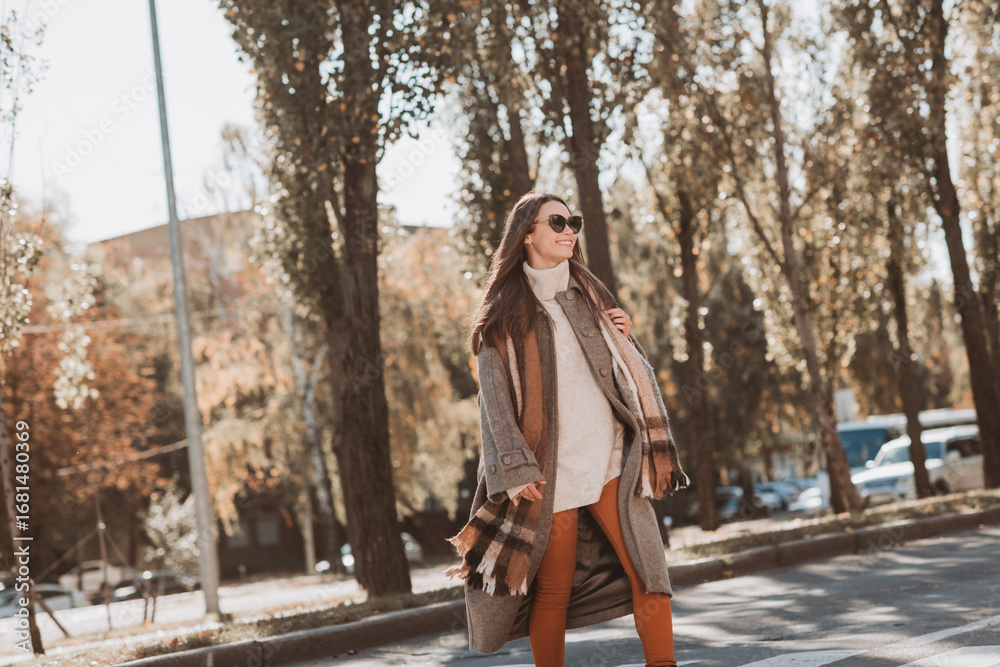Fototapeta premium Glamorous woman enjoying a sunny autumn day walking outdoors with confidence and style