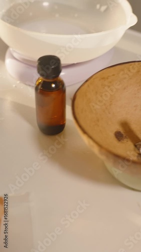 Vertical video. Sunset light over table with candle making supplies, amber bottles, wax bag, coconut bowls and pot, wide angle. Concept Cozy Home Decor
