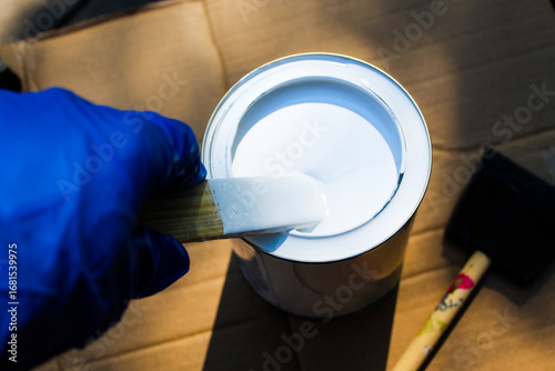 a person stirring a can of white paint or primer with a wooden stick. home improvement background.