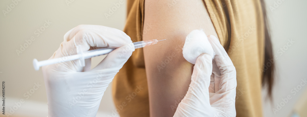 Fototapeta premium People getting a vaccination to prevent pandemic concept. Woman in medical face mask receiving a dose of immunization coronavirus vaccine from a nurse at the medical center hospital