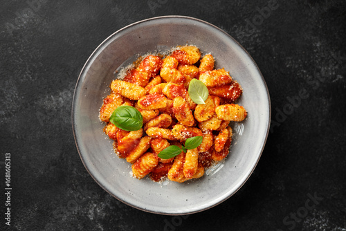Traditional Italian potato gnocchi with tomato sauce, parmesan cheese and fresh basil leaves on black background, top view	