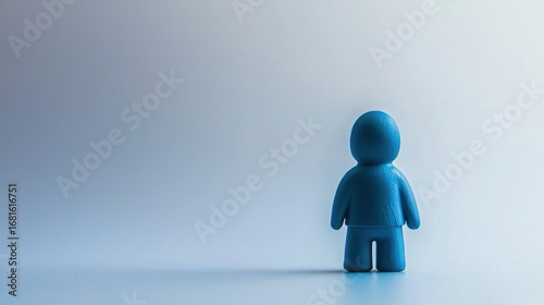 A blue figurine stands alone against a plain background, casting a shadow on the floor.