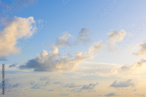 Beautiful cloudscape image of detached fluffy cumulus clouds light blue sky sun setting.
