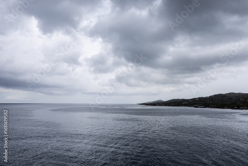Ocean horizon small piece of land dramatic grayish cloudscape background image