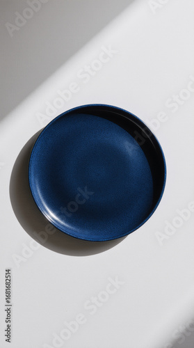Round blue ceramic plate centered on soft white background minimal clean tableware design
