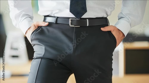 Businessman in suit hands-in-pockets, standing confidently in front of whiteboard, likely at an office meeting.