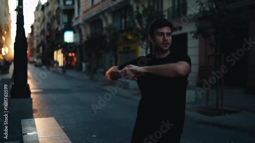 Man stretching arms on city street at sunrise, preparing for workout. Represents discipline, motivation, and morning fitness routine with focus on wellness and balance.

