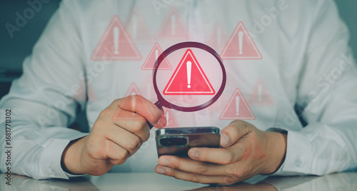 Man holding smartphone with red warning icons indicating error, risk, or cyber threat alert in digital system or app.