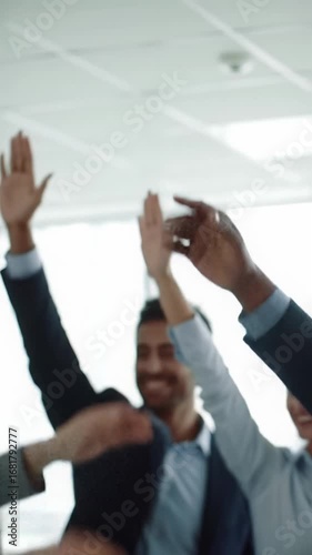 Medium close-up video capturing diverse professional hands rising in unison in a bright, modern corporate meeting room, signifying unanimous approval. Business consensus concept