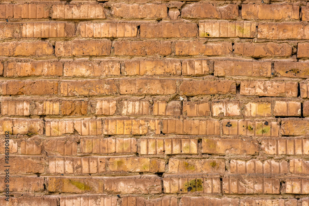 Obraz premium A detailed shot presents an old brick wall showcasing a weathered texture with visible signs of age and wear. The rustic masonry features cracked and uneven surfaces, with a palette of brown and