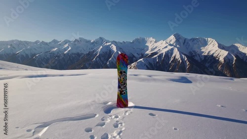 Snowboard positioned upright in the snow against the stunning backdrop of the pristine white Caucasus mountain range