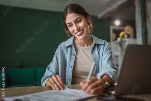 Fotografija Young businesswoman signing contract at home office desk smiling happily