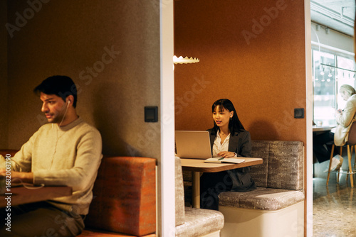 Female corporate business professional talking on video call through laptop while sitting in coworking office