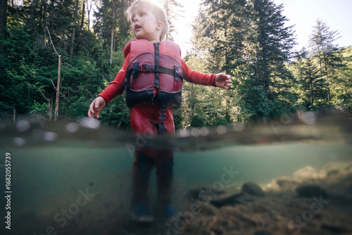 A toddler enjoys walking in the water of a clear river in the Pacific Northwest.