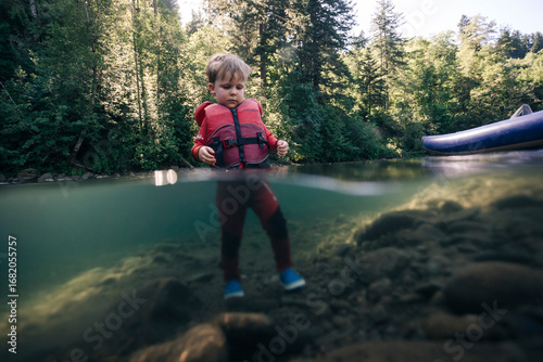 A toddler enjoys walking in the water of a clear river in the Pacific Northwest.