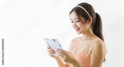 Smiling woman reading a brochure, happy expression, pastel dress, white background, female portrait, marketing material, announcement, invitation, positive emotion