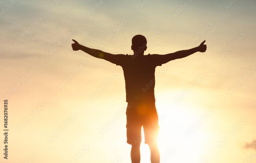 Obraz premium silhouette of a man standing with open arms, embracing the warmth and light of the sun, evoking a sense of , praise, worship, freedom, positivity, and joyful connection with nature and self