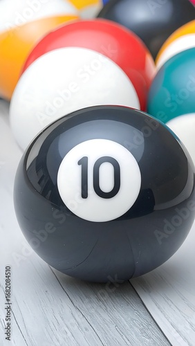Close-up view of a billiard ball numbered ten, resting on a light-colored wooden surface amidst a group of other billiard balls.