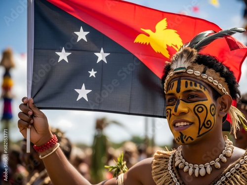 Young man in traditional attire holding a Papua New Guinea flag during a festival, celebrating independence day in Port Moresby.