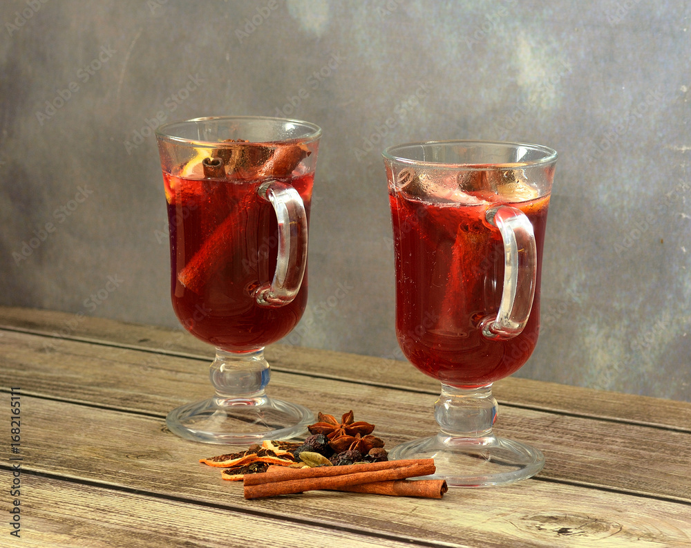 Φωτογραφία Two glasses of hot red wine with pieces of citrus and spices on a wooden table