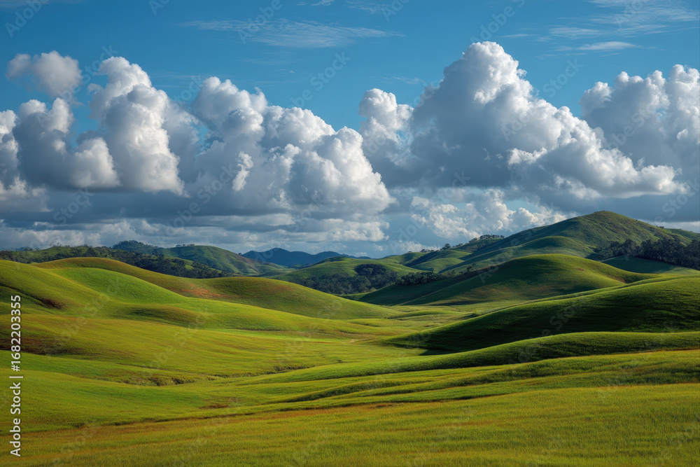 Fototapeta premium Rolling green hills under a bright blue sky with scattered clouds