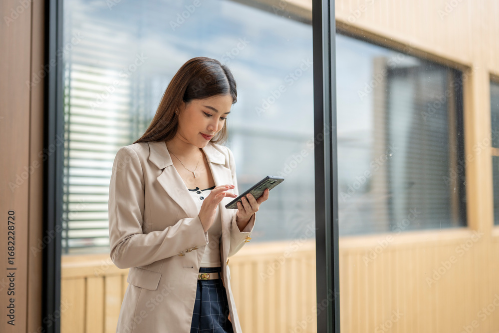 Fototapeta premium Businesswoman using mobile phone by the window in modern office