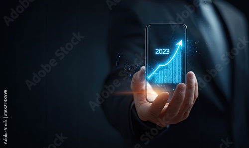 Businessman holds a phone displaying a glowing 2023 growth chart
